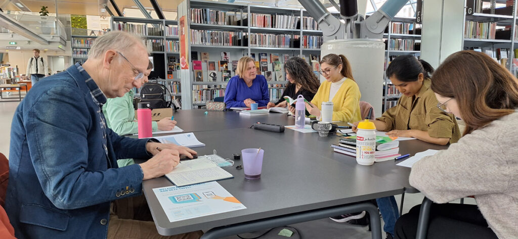 Dianne Kikstra met cursisten aan een tafel in de bibliotheek