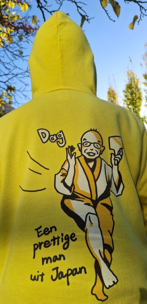 achterzijde van een gele hoodie met de tekst "een prettige man uit Japan."